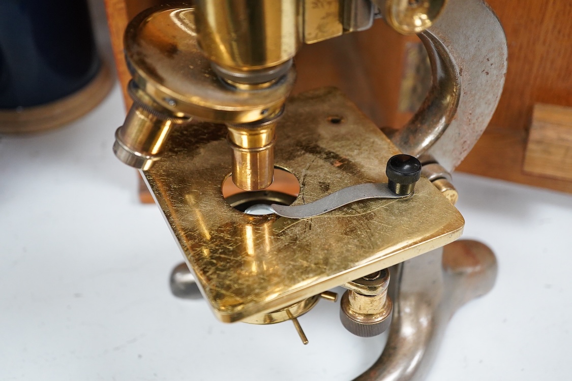 An early 20th century oak cased brass ‘Kima’ microscope by W. Watson & Sons Ltd. London, with engraved serial number under the maker’s name; 53622, with two alternative lenses in fitted compartments, microscope approxima